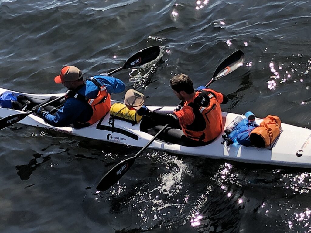 Bart Maupin, a Washington highway patrol officer, and Marc Fuhrmeister paddle in unison on their white kayak.