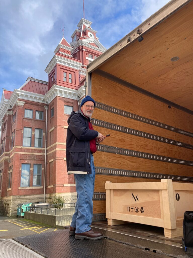 Paul Brower turns to the camera as he gets a sculpture get packed into a crate onto the back of the van.