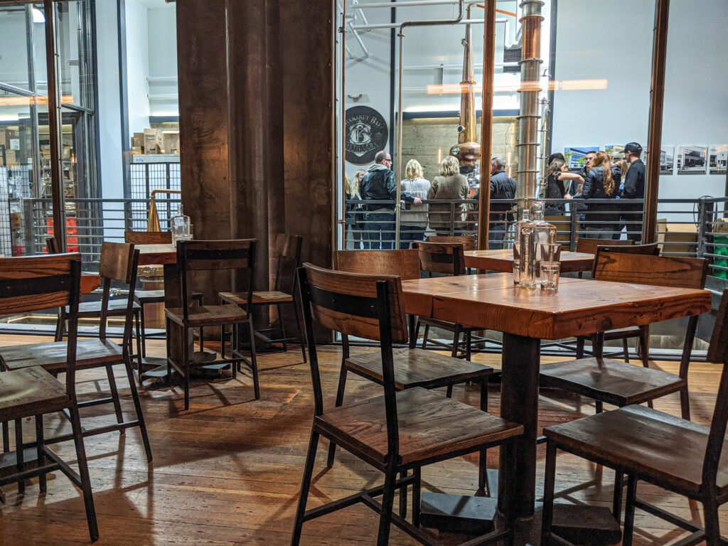 The main dining space at Penny Farthing is narrow and dark with rich, finished wood and slightly steampunk-feeling details next to windows that show tours taking place.