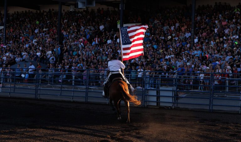 A rider on a horse parades the American flag around the arena.