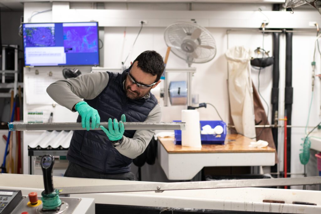 Erick Bravo, an imaging specialist, holds up a tray of core samples collected by the Joint Oceanographic Institutions.