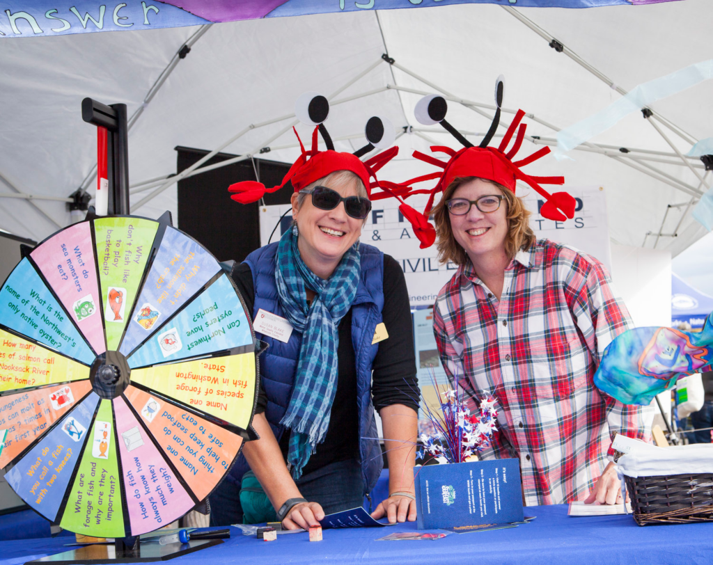 Wearing red crab hats, booth hosts welcome attendees with pamphlets and games.