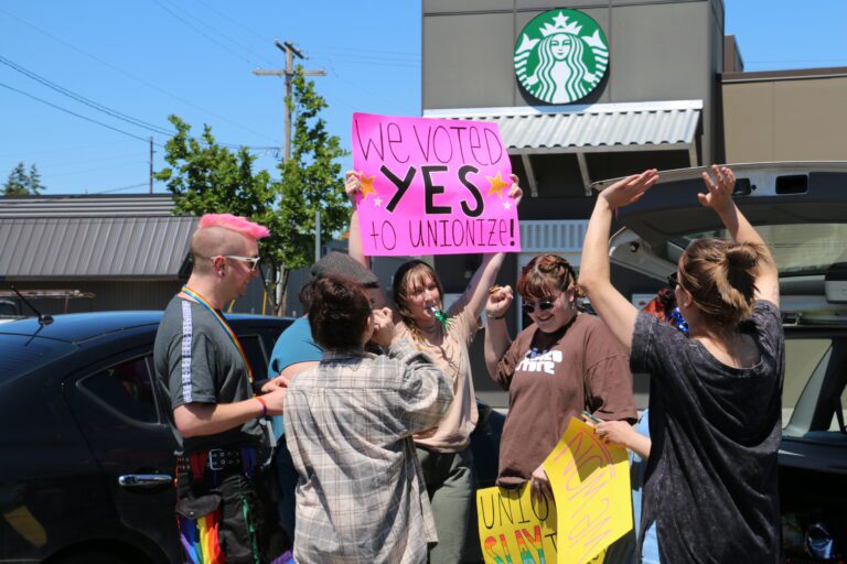 Starbucks employee Shannon Butler, center, holds up a sign as she and her coworkers celebrate a unanimous vote to unionize.