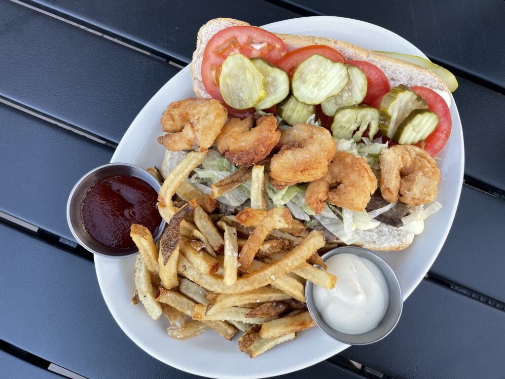 Surf & turf po’ boy served with French fries and dipping sauces.