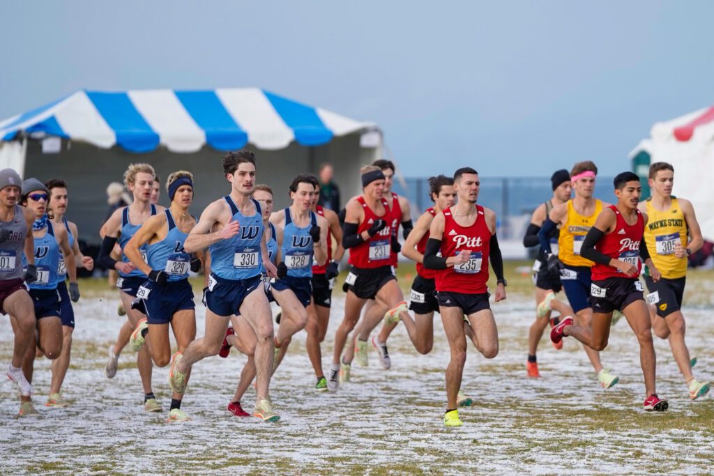 The Western men's runners race as a group next to other competing teams.