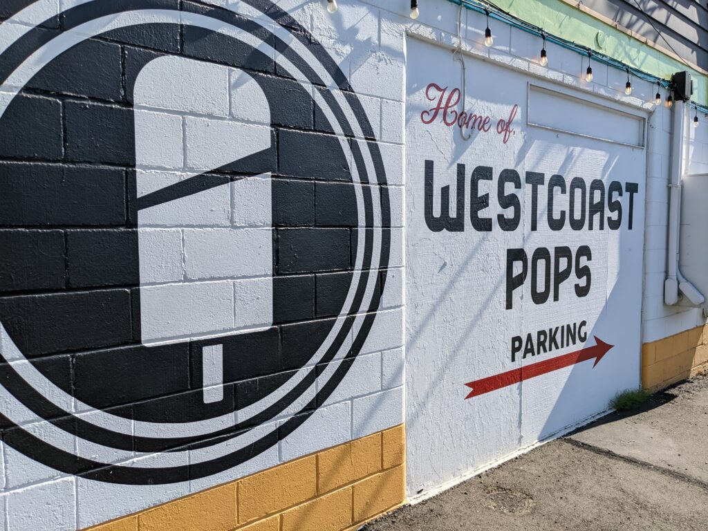 The now-former offices of West Coast Pops has a mural of their logo and directions for their parking.