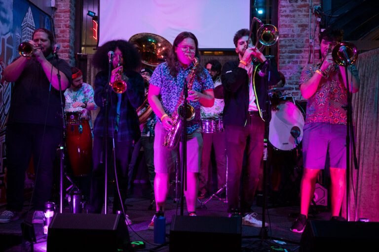 Analog Brass performs at the Kulshan Trackside stage underneath a bright purple light.