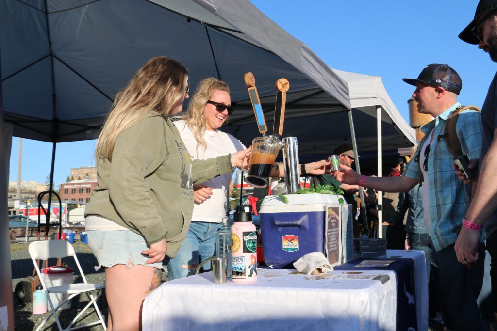 Julie Voight-Peif, left, fills up her pitcher with beer while Jessie Mattingly, right, hands off a beer tasting to an attendee as others wait for their turn.