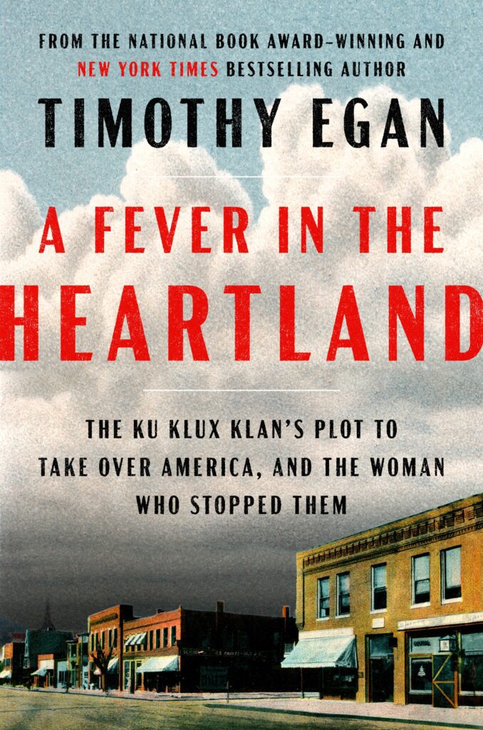 The book cover of "A Fever in the Heartland" has buildings and heavy clouds looming over the town.