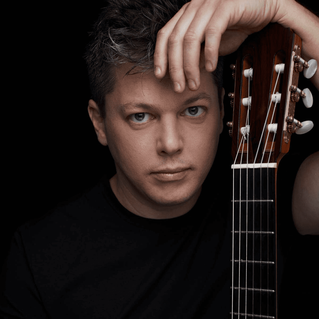 Guitarist Daniel Bolshoy leans on his guitar.