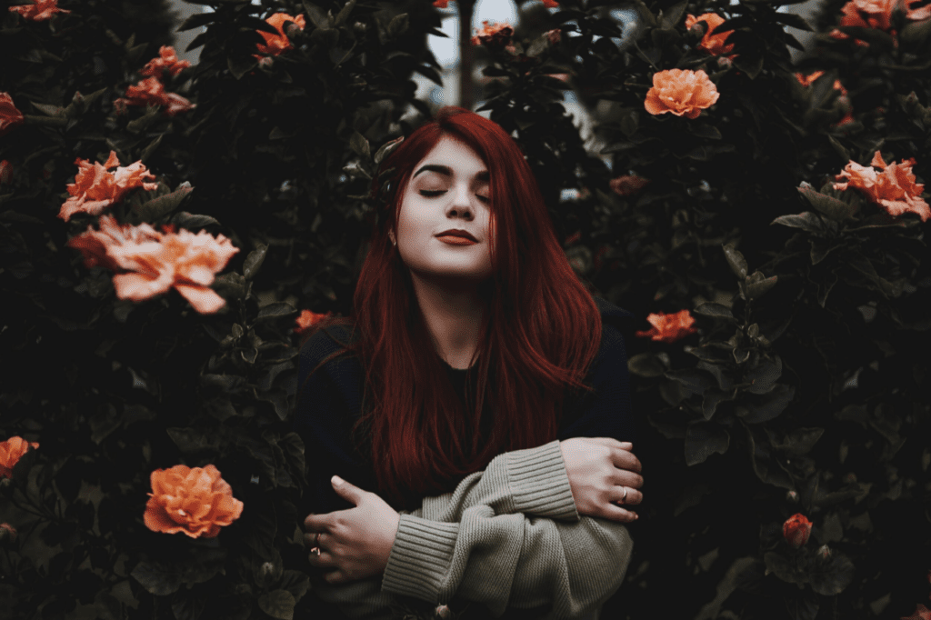 Jessie Ulmer crosses her arms in between rose bushes.