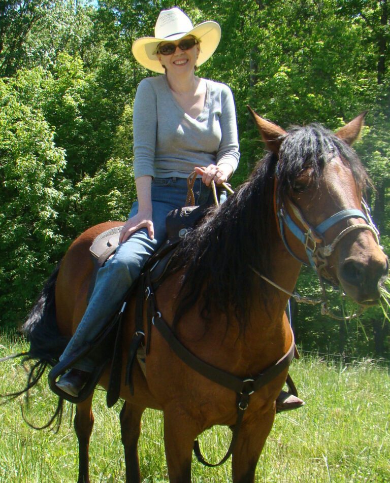 Mary Doria Russell smiles from on top of her horse.