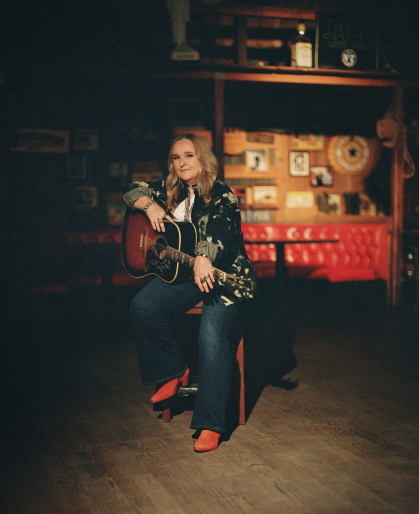 Melissa Etheridge sits with her acoustic guitar.