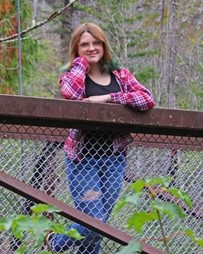 Melody J. Thompson leaning against a railing and smiling.