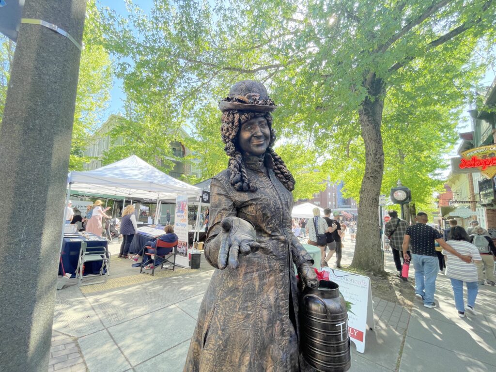 In front of Jalapeños restaurant on Harris Avenue, a painted person meant to look like a rusted statue extends a hand to the camera.