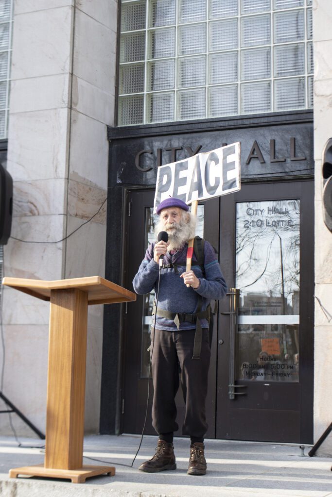 Bromet sings "Peace, love, joy, truth, good, enlightenment of humanity" to the tune of Beethoven's Symphony No. 9, Ode to Joy, at a protest at the entrance of Bellingham City Hall.