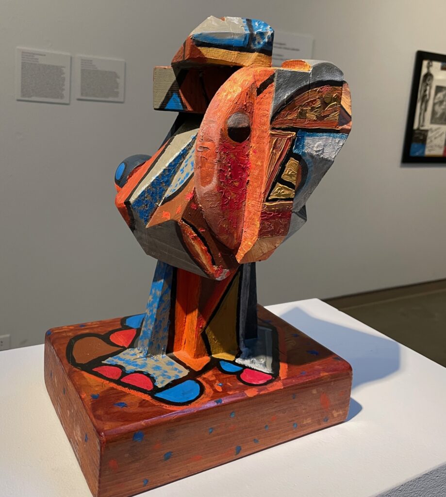 A large and dramatic “Polychrome Head” on display on a white podium.