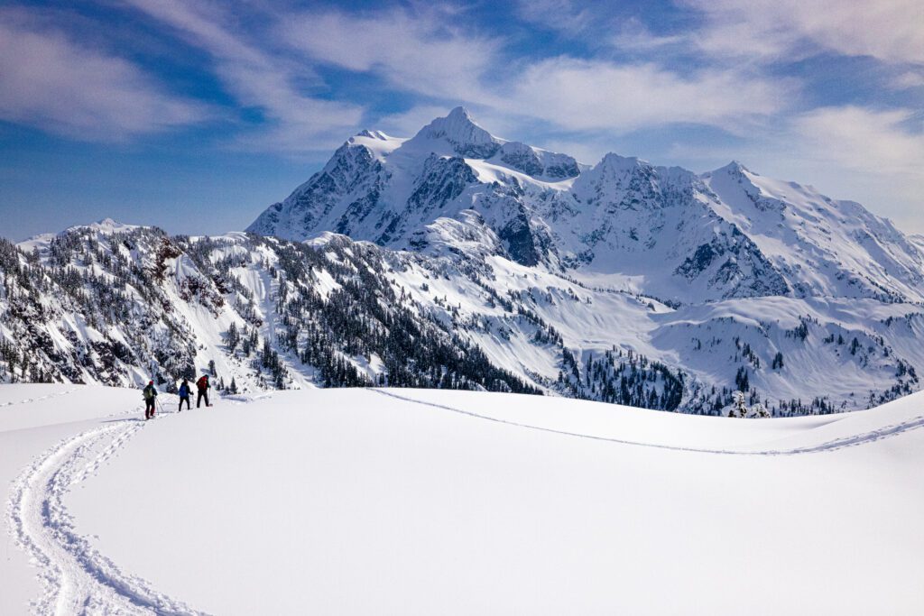 Views of Mount Shuksan, snowshoers make their way through the snow.