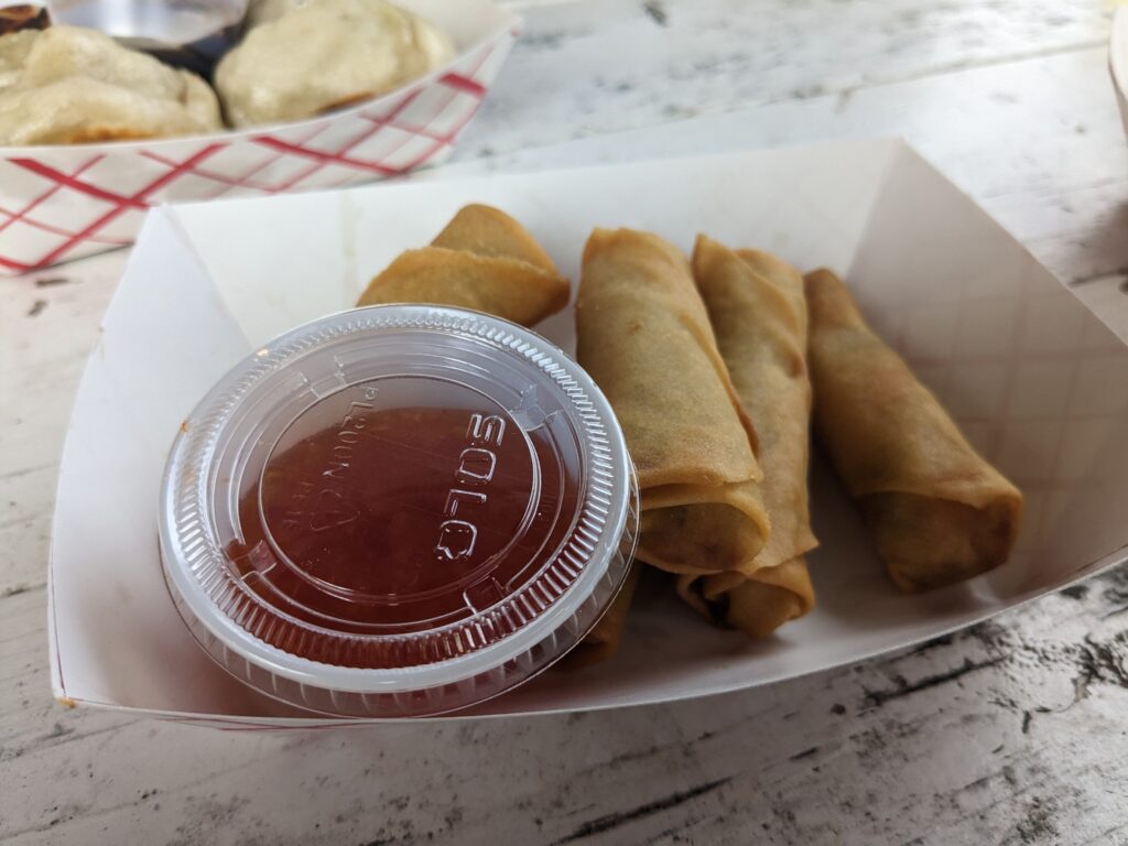 Vegetarian spring rolls served with a side of sweet and sour sauce.