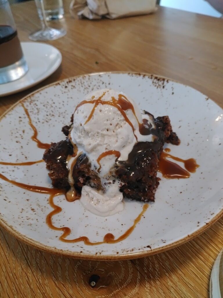 The sticky date cake served with ice cream and drizzled with caramel sauce.