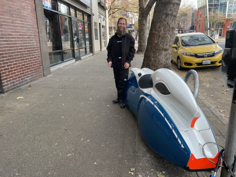 Zach West stands in front of his Quatravelo, a pedal-powered, custom-built bike.