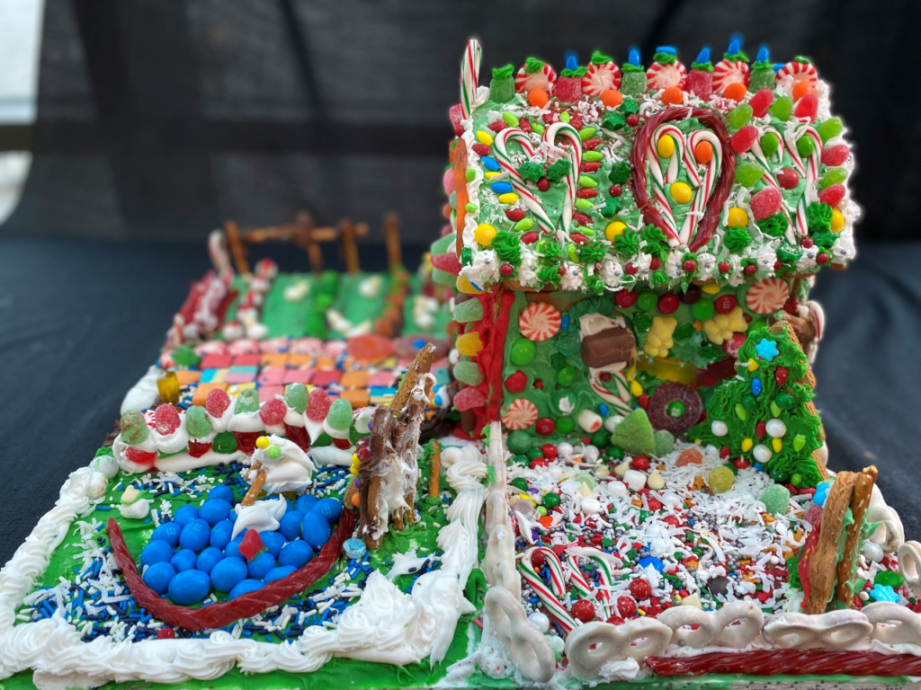 A gingerbread house covered in candy with multiple lawns.