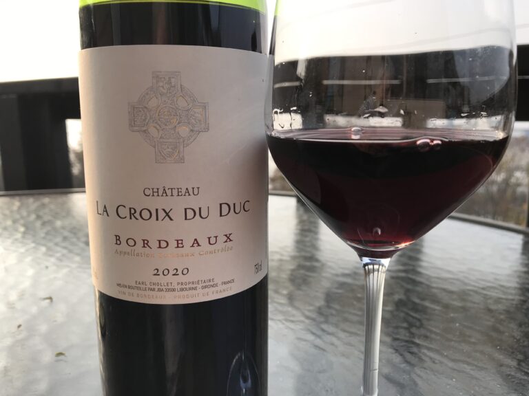 The 2020 Chateau La Croix Du Duc next to a wine glass.