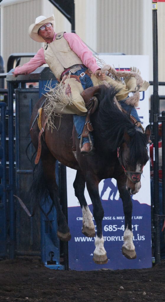 A saddle bronc rider holds onto the bucking horse as hard as he can.