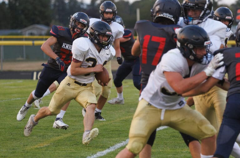 Meridian’s Josh Elmer runs in for the touchdown as another opposing team's player runs right behind him while both teams brace against each other.