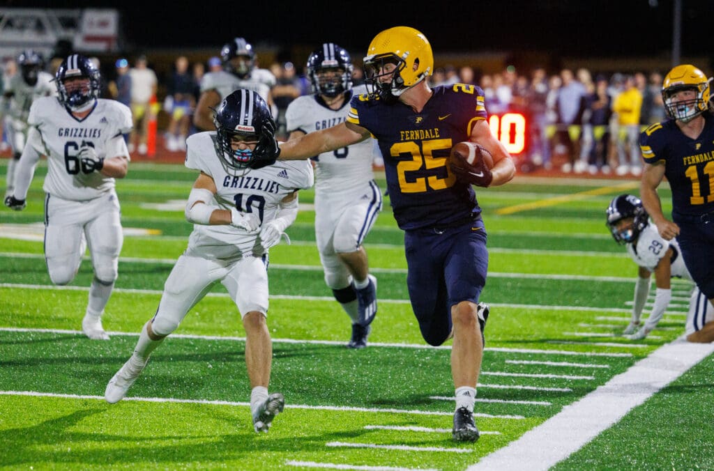 Ferndale’s Conner Walcker pushes away a Glacier Peak defender with one hand as other defenders and his teammates rush over.