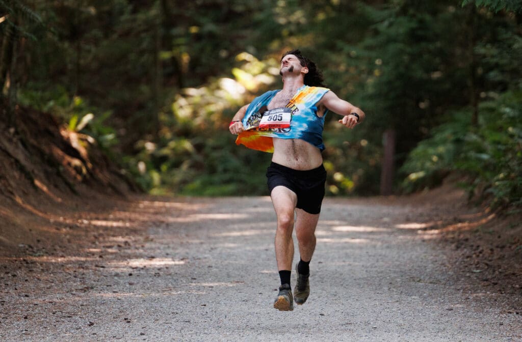 A runner tears at his shirt as he runs down the Lake Padden trail.