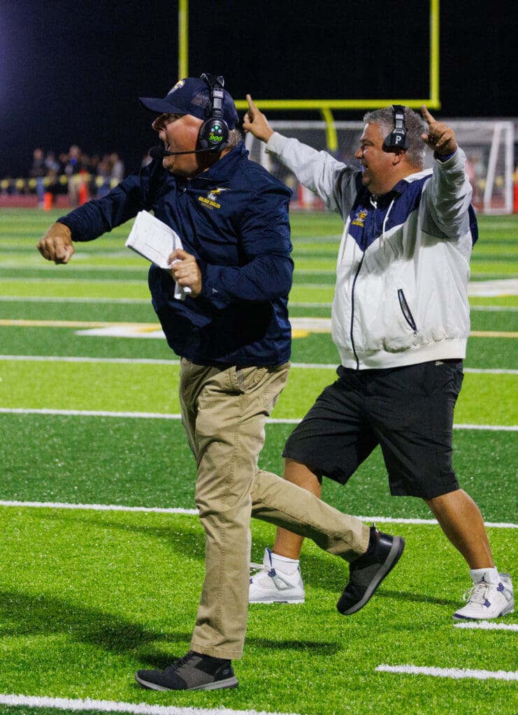 Ferndale head coach Jamie Plenkovich, left, punches the air in celebration as his assistant coach celebrates with both his hands in the air.