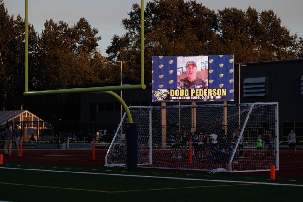 On a new screen, Jacksonville Jaguars head coach and Ferndale graduate Doug Pederson cheers on the Golden Eagles as the sun sets, dimming the sky behind the screen.