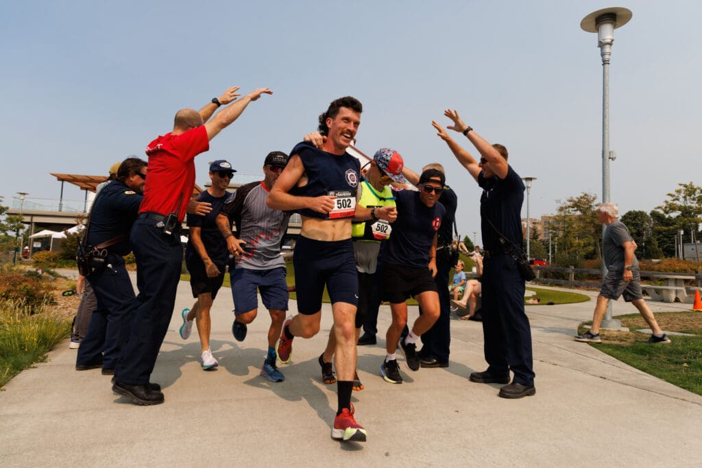 The Bellingham FireFighters team runs under the outstretched arms of colleagues near the finish line.