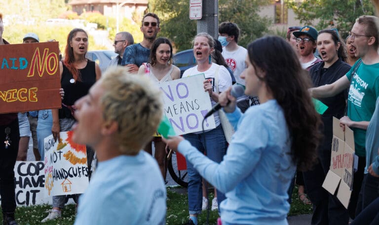 Protesters yell as speakers recount each time a new jail was rejected by voters while holding signs in protest.