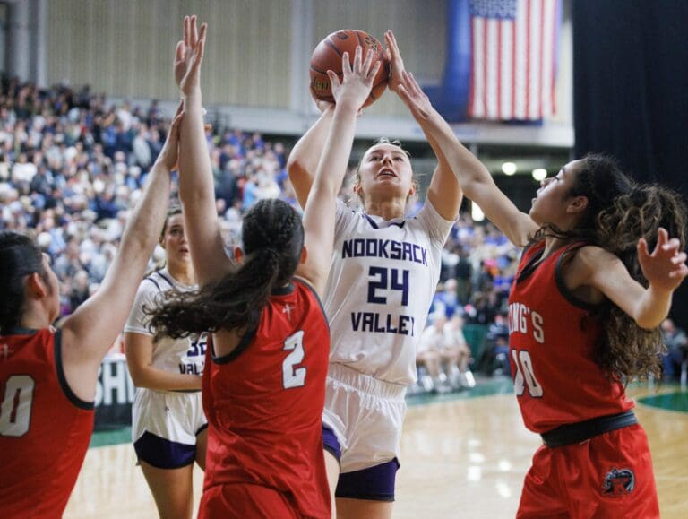 Three King's defenders try to stop a shot by Nooksack Valley's Devin Coppinger as they reach over her with their arms extended.