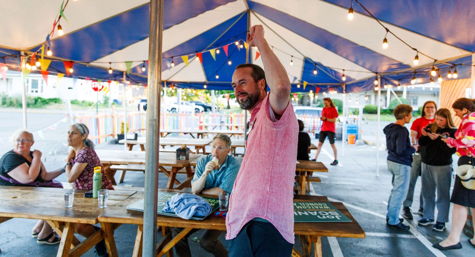 Jon Scanlon reacts to results as he cheers with one fist in the air.