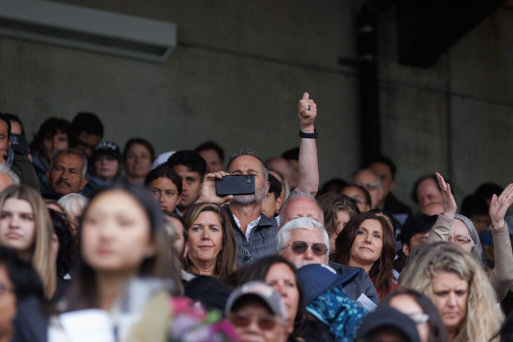 One parent takes photos and gives a graduate the thumbs-up sign.