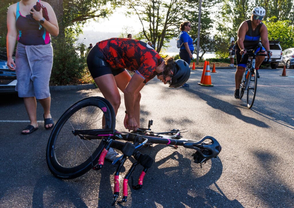 Cheryl Schmitt fixes her chain that fell off while setting off for the bike leg.