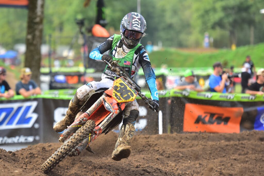 Jacob "JJ" Concannon focuses on a turn on his dirt bike as spectators watch from behind a barrier.