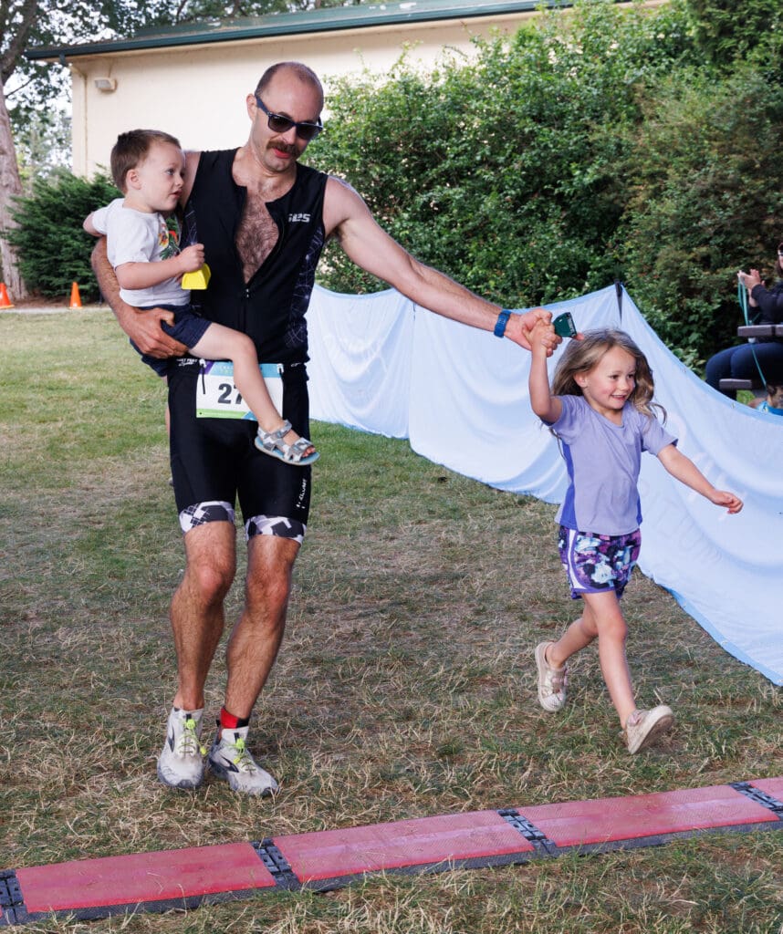 Andy Jerome carries his son Hadrian while racing to the finish with his daughter Rosalind.