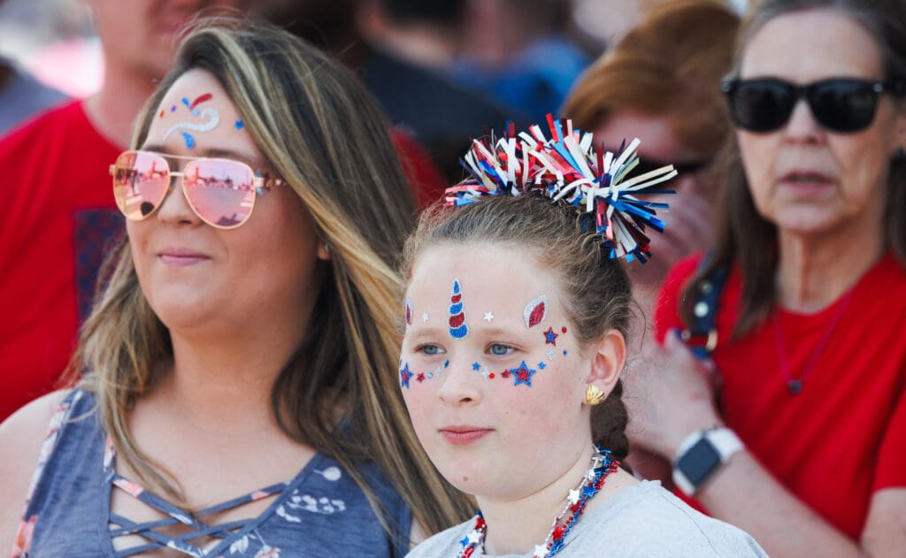 Katie Schloemer and daughter Adison sport red, white and blue facial decorations as they watch the parade.