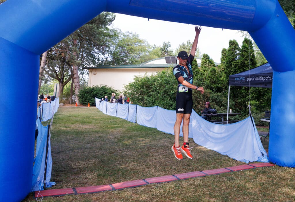 Racer Luke Hurst leaps and touches the arch of the finish line.