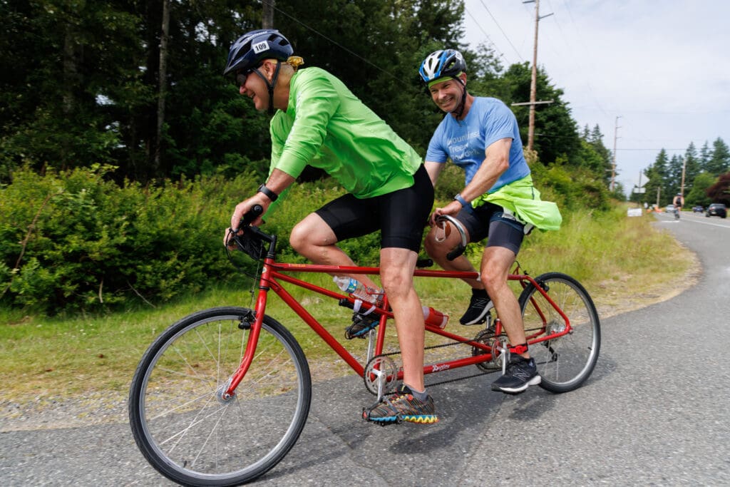 Two riders compete on a tandem bike.