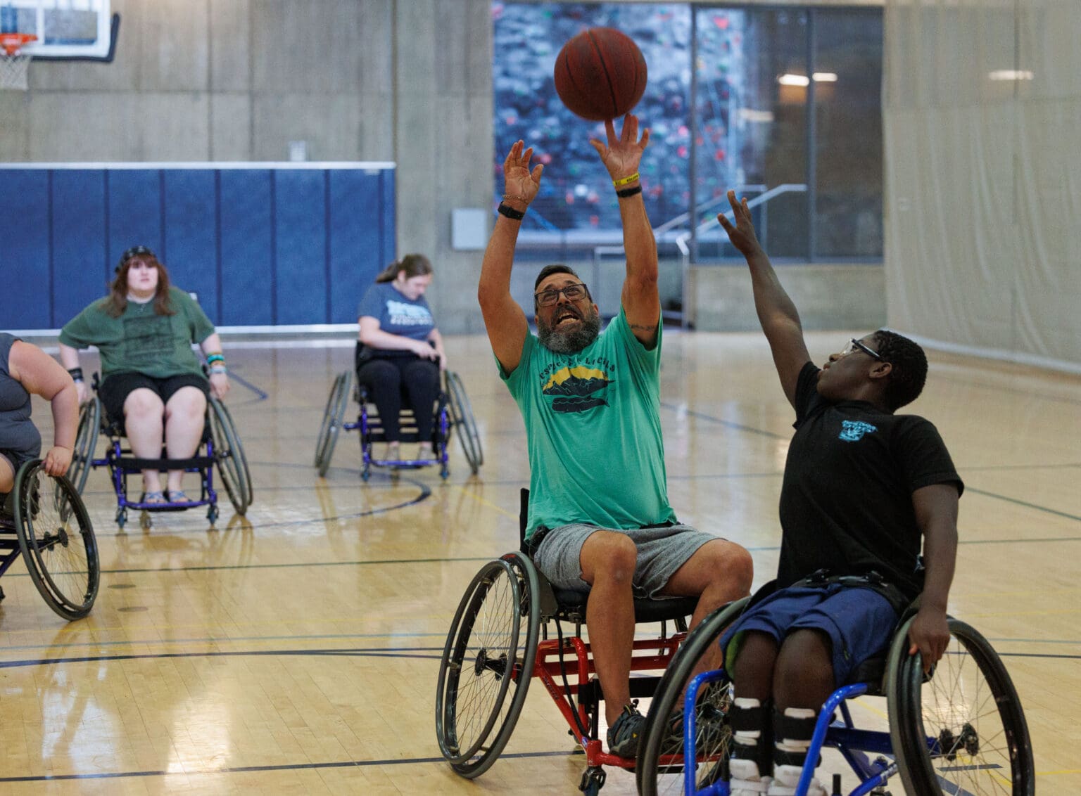 Bob Gammons-Reese shoots a basketball over his son, Jude, as other players watch nearby.