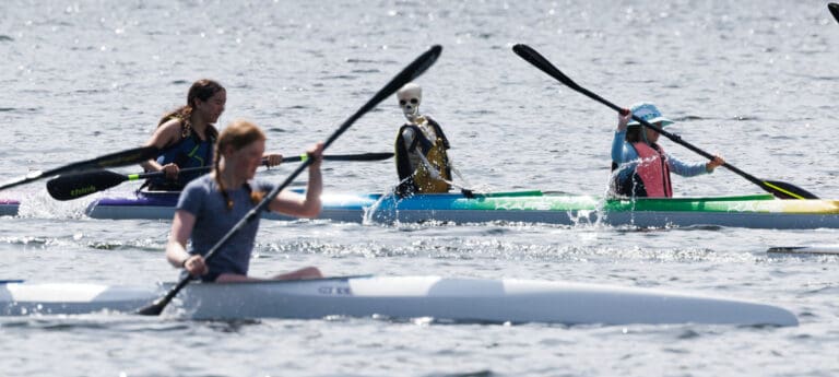 Sully the skeleton appears to be watching as a four-person team is passed by a single rower.