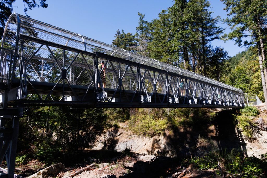 People walk across the new bridge covered with a chain linked fence for their protection.