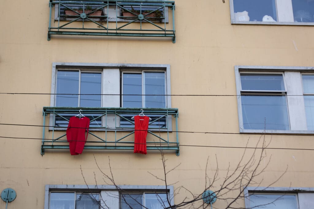 Two red dresses, symbolizing missing and murdered Indigenous women, hang from a window above Alexander Street.