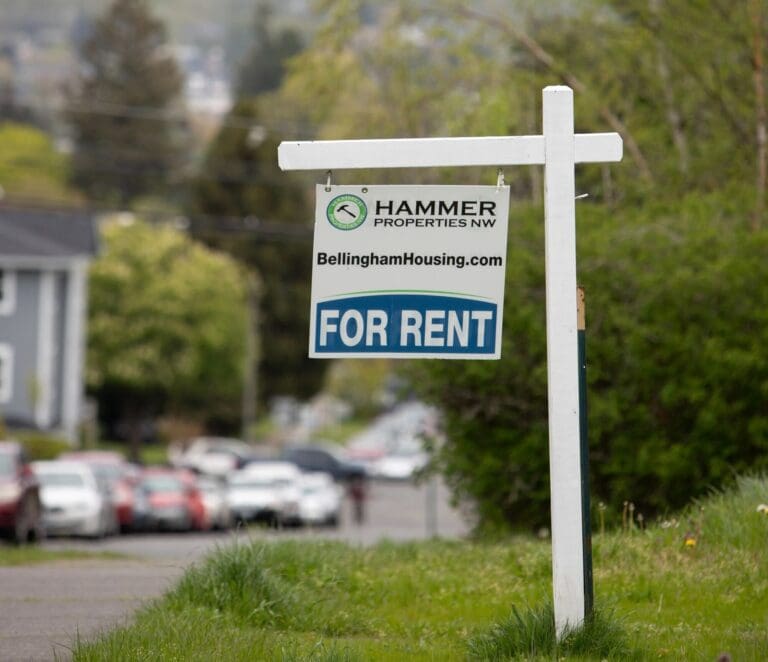 A for rent sign hangs on a white pole.