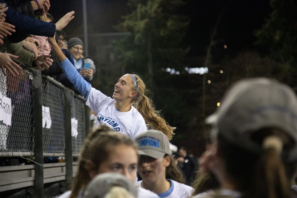 Claire Potter high-fives fans who are cheering her team on from the bleachers.